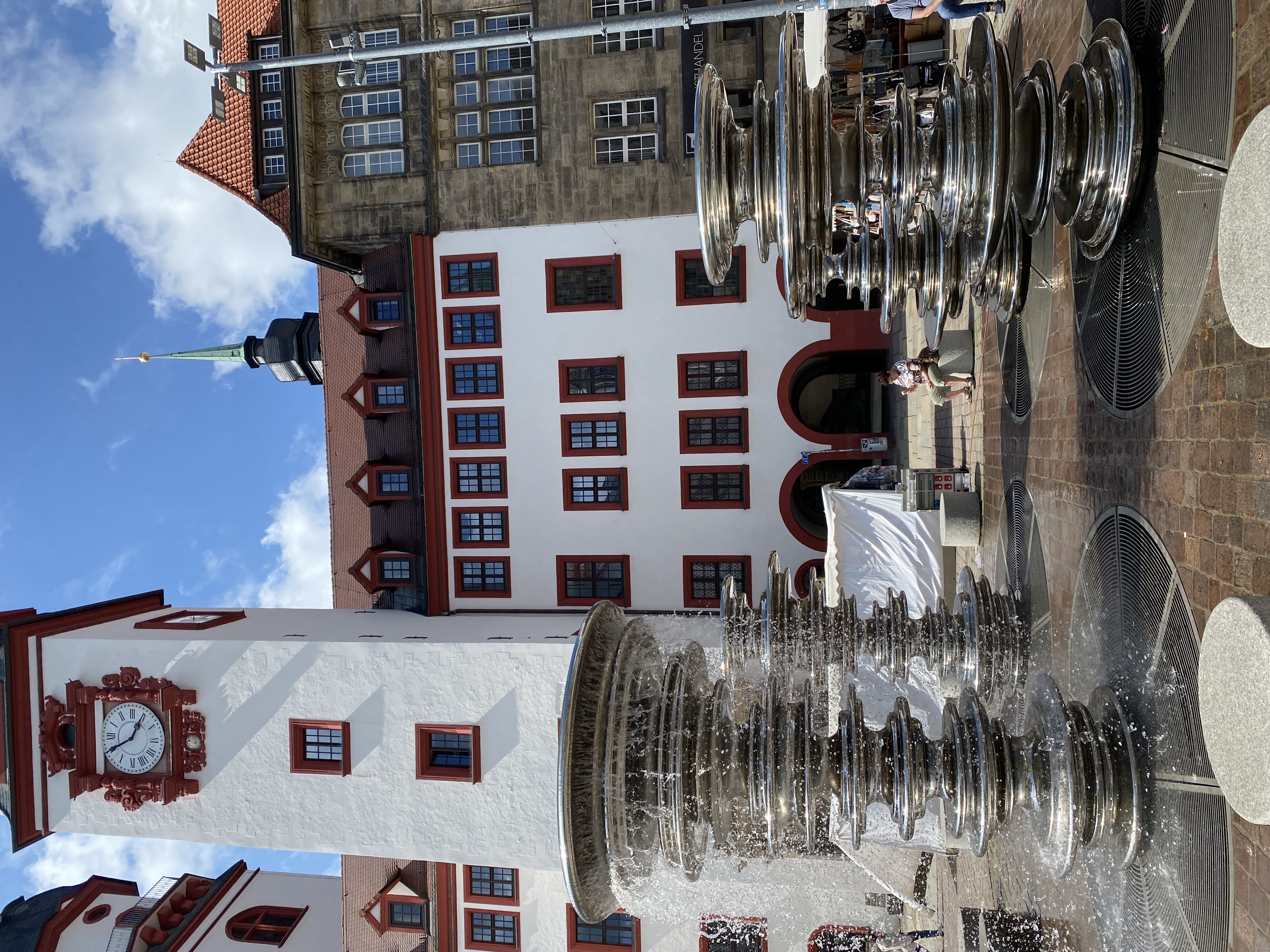 Ein schöner Brunnen vor einem Gebäude, das einen auffälligen Uhrturm hat.