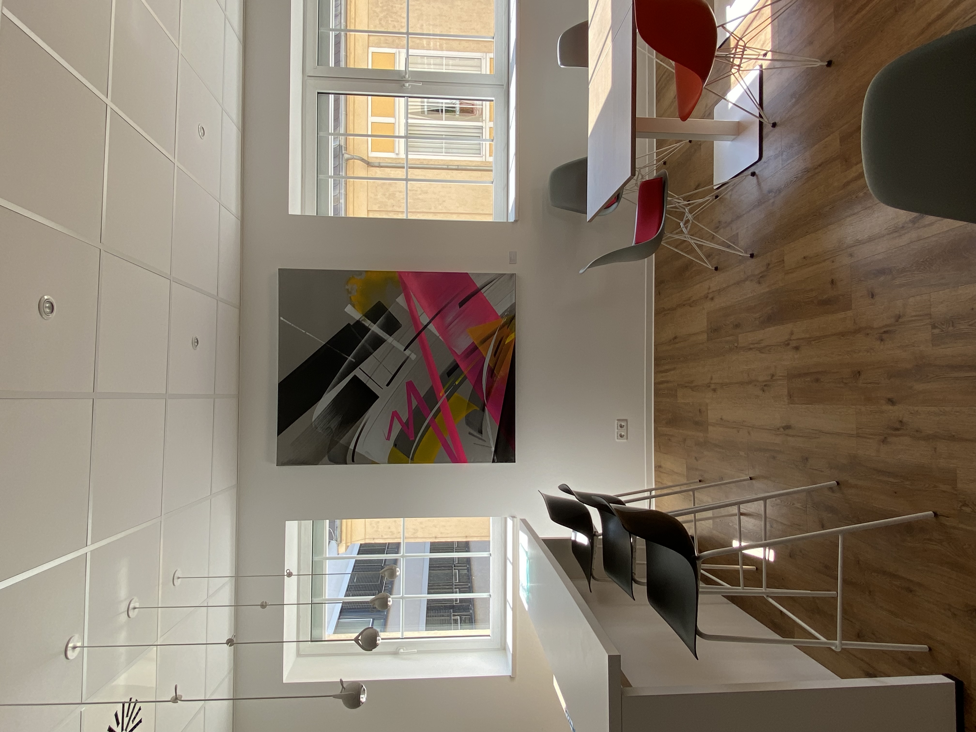 Blick in ein Büro mit buntem Kunstwerk an der Wand.
